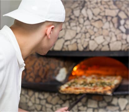 Chef cooking in commercial pizza oven